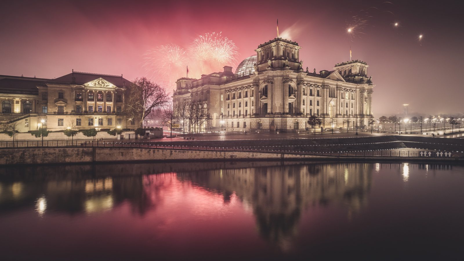 Berlin's Reichstag building by night, shot from the other side of the Spree, with fireworks in the background. Picture used to illustrate an article on plans for a moat for the Reichstag.