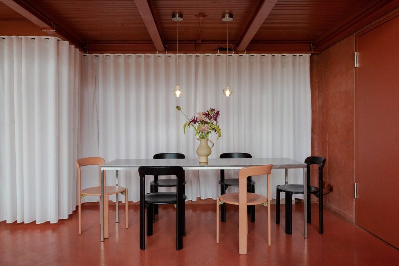 Blick in roten Raum mit weißen Vorhängen, Tisch mit schwarzen und lachsfarbenen Stühlen. Interieur Restaurant Lok 6.