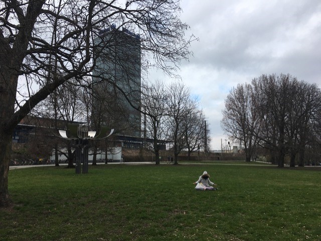 Leere Wiesen im Treptower Park in Berlin. Eine einsame Person meditiert inmitten der Corona Pandemie.