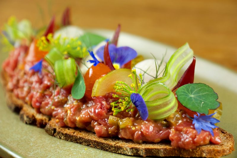 Tartar auf Brot mit essbares Blüten und Blättern belegt. Das Restaurant Christopher's in Charlottenburg ist noch offen für Take-away Lieferung