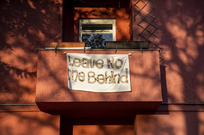 Balkon mit Plakat "Leave No One Behind", Beispiel für politischen Aktivismus trotz Corona.