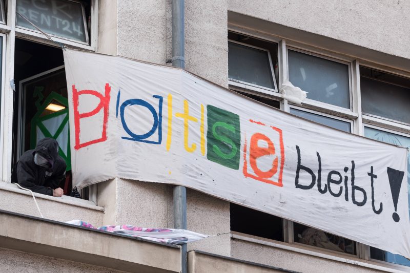 Maskierte Aktivisten schauen aus dem Fenster der während der Kundgebung vor dem besetzten Jugendclub Potse und Drugstore am 2. Januar 2019 in Berlin.