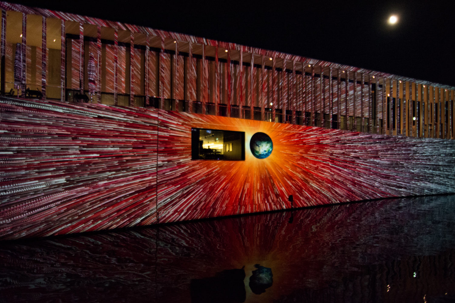 Wie in einem Raumschiff rauscht man bei diesem Bild mit Lichtgeschwindigkeit auf die Erde zu, projiziert an die Fassade der James-Simon-Galerie.  Foto: Imago/McPHOTO