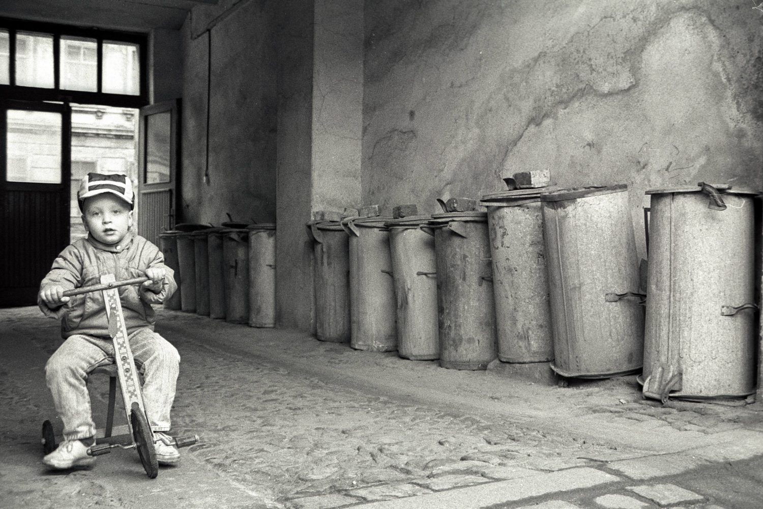 Einsamkeit in Berlin: Einsamer Junge fährt Dreirad in einem tristen Berliner Hauseingang, 1989. Foto: Imago/Dieter Matthes