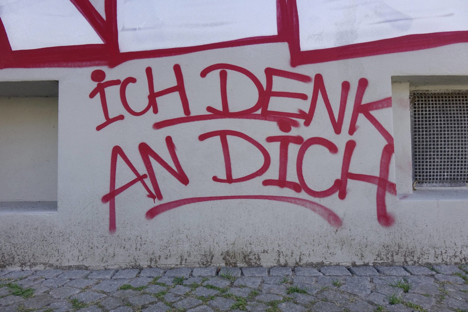 Graffiti "Ich denk an dich" an einer Hauswand.
