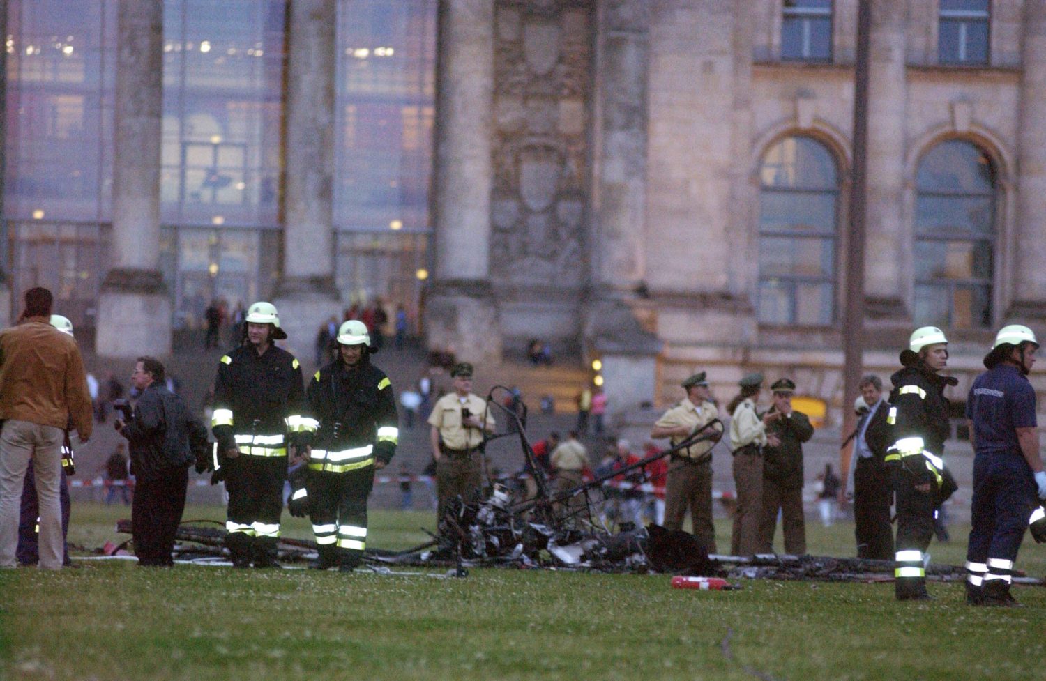 BNach dem Absturz eines Ultraleichtflugzeugs vor dem Berliner Reichstag begutachten Einsatzkräfte das verkohlte Flugzeugwrack, 2005. Foto: Imago/Seeliger
