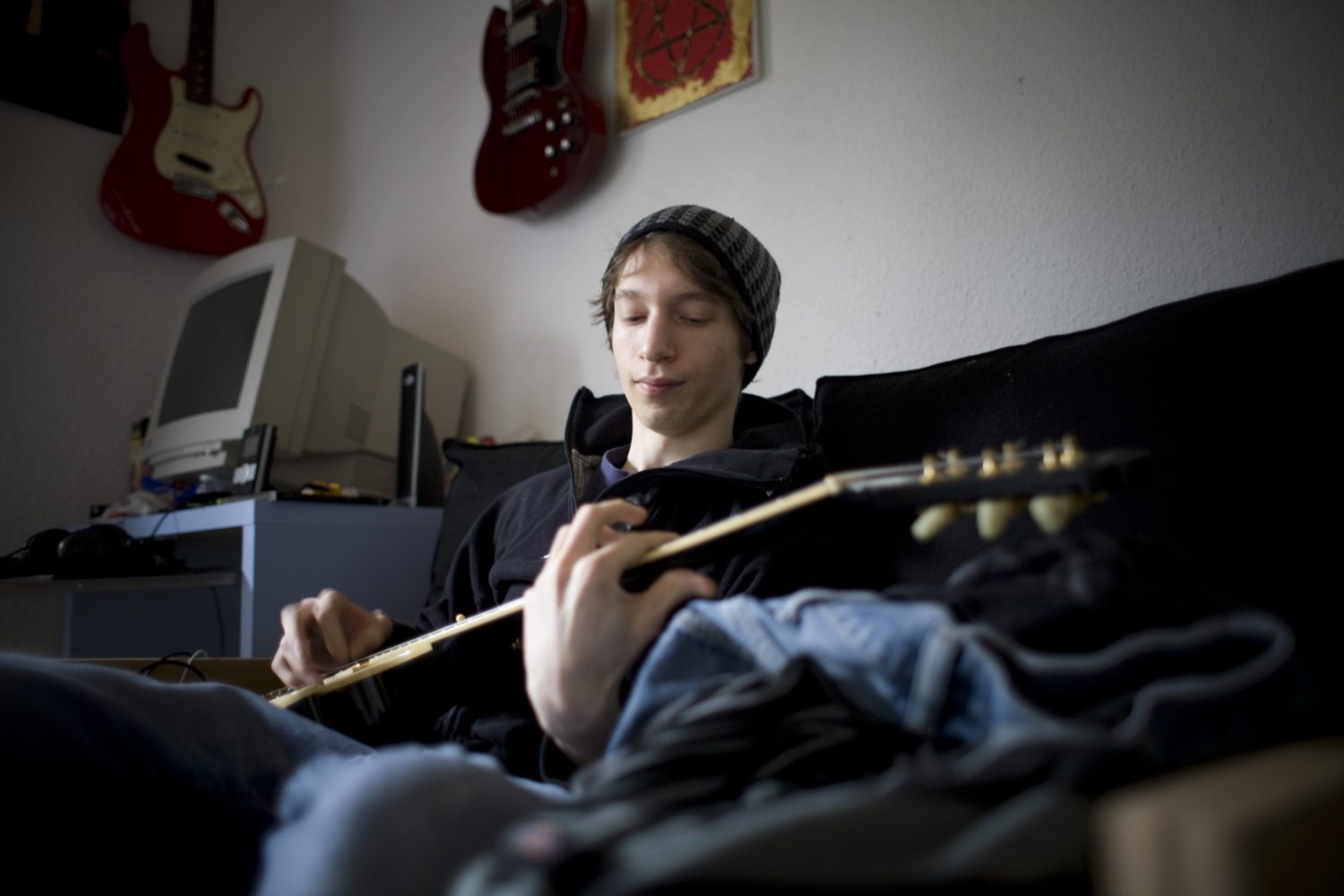 Alternative Lebensformen Berlin: Untermiete statt Miete. Ein junger Mann spielt in seinem Zimmer Gitarre. Foto: Imago/Photothek/Ute Grabowsky