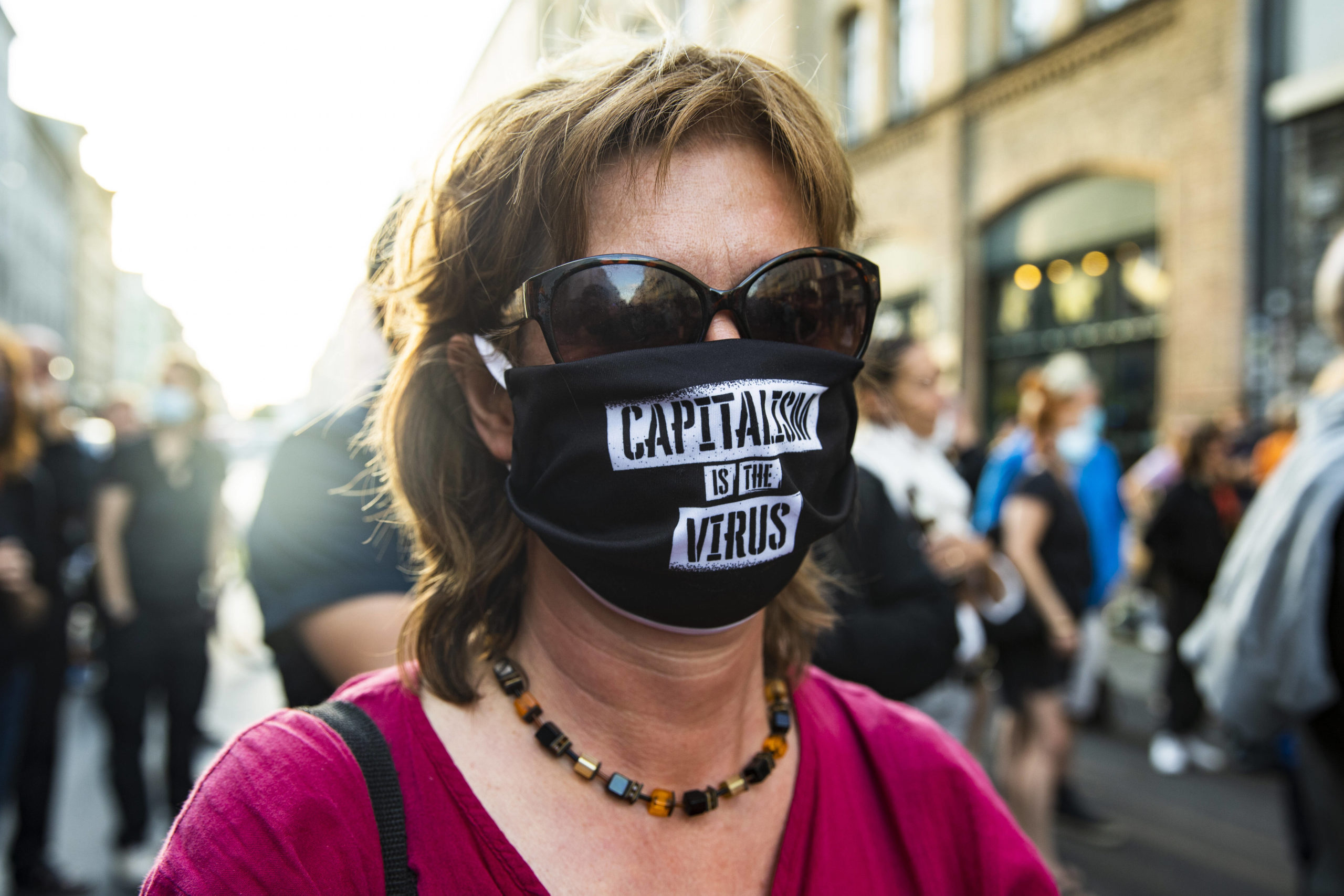 Eine Frau mit Maske mit dem Schriftzug "Kapitalismus ist der Virus" protestiert gegen der Schliessung der Buchhandlung Kisch & Co. Foto: Imago/Emmanuele Contini