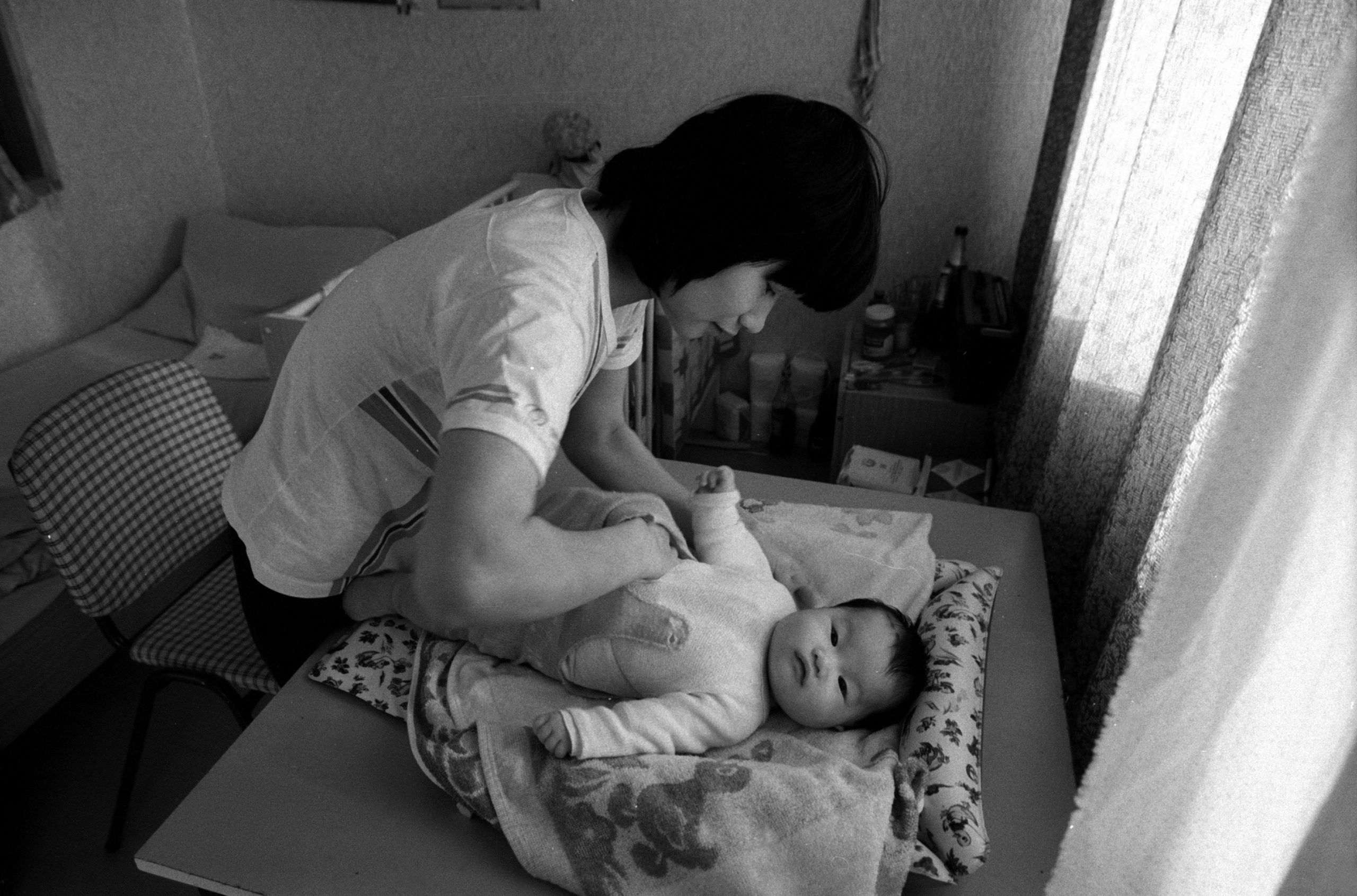 Vietnamesische Vertragsarbeiterin windelt ihr Baby im Wohnheim. Foto: Imago/Werner Schulze
