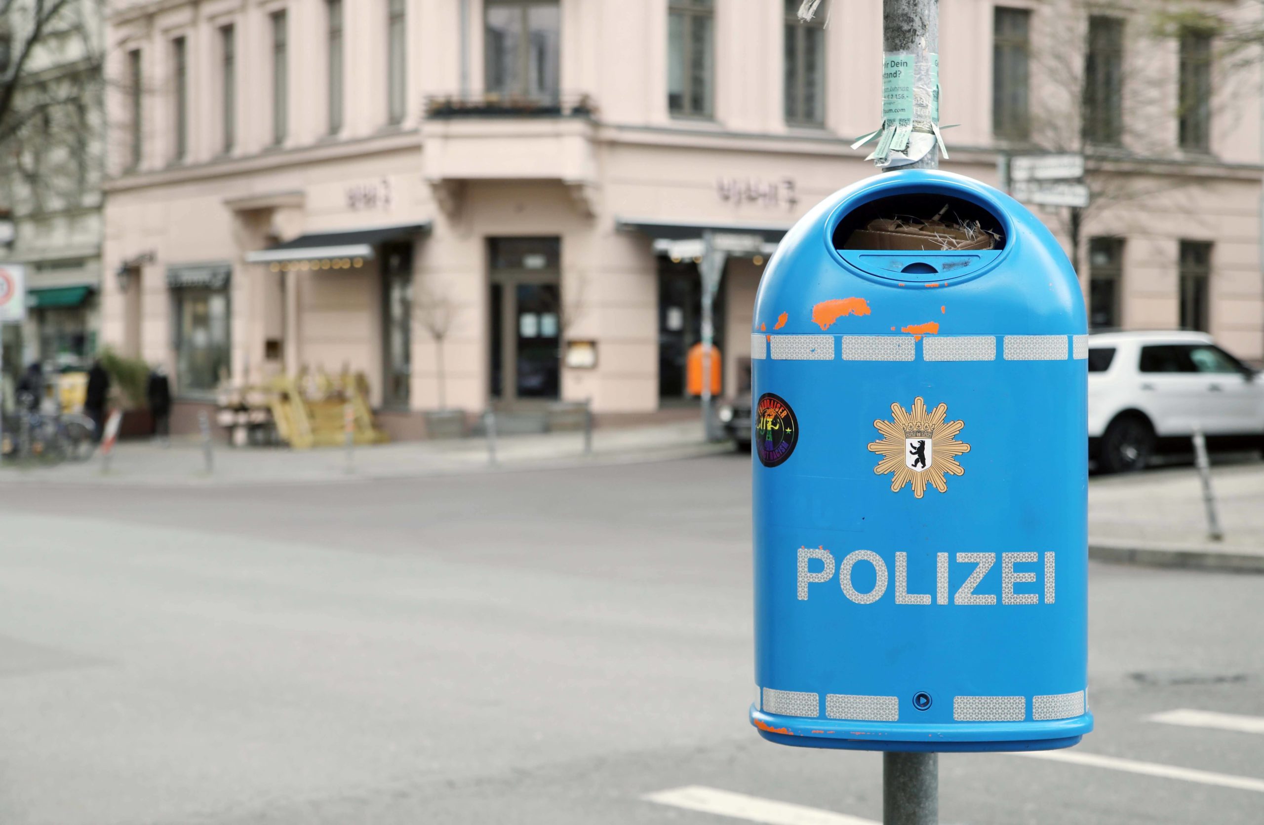 Lustige Berlin Fotos: In Kreuzberg hängt ein blauer Papierkorb mit Polizeilogo an einem Mast. Foto: Imago/Sabine Gudath