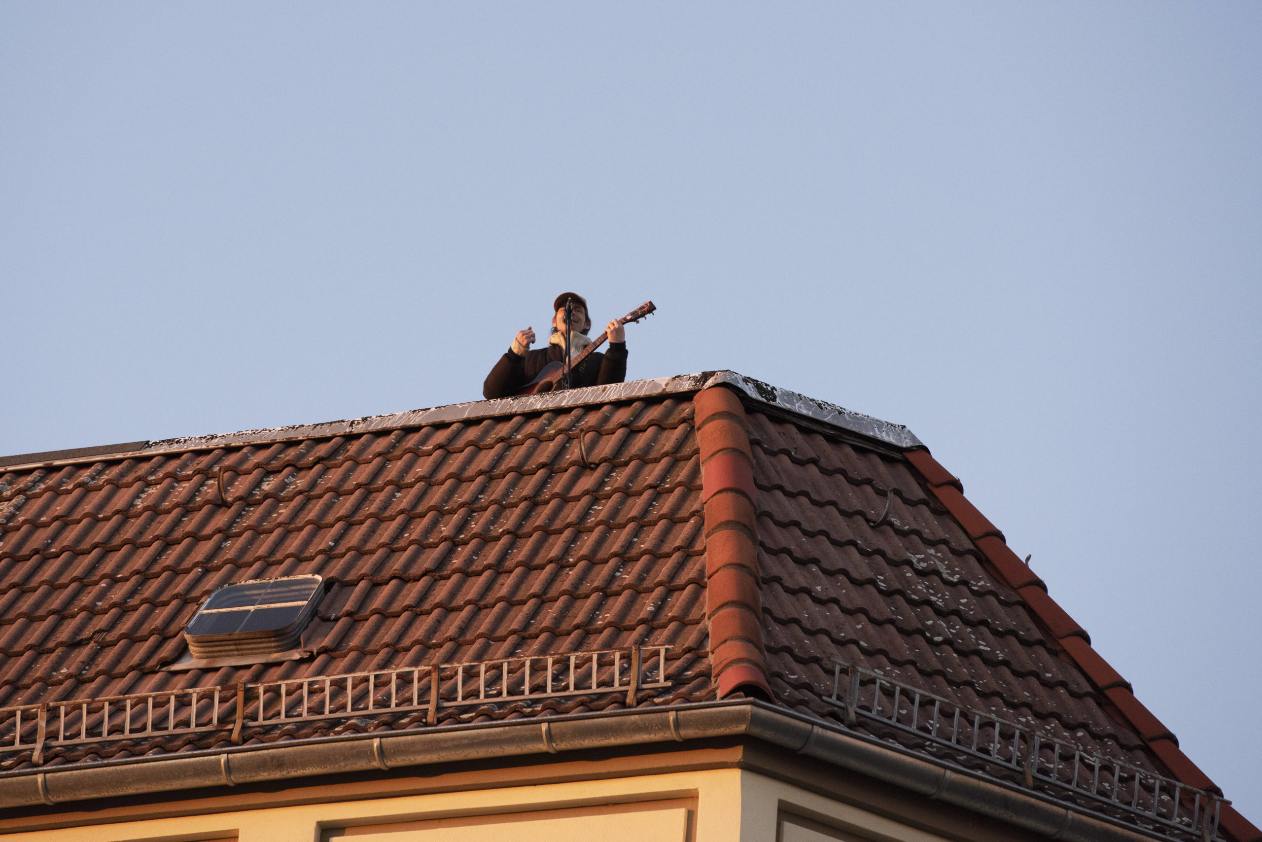 Musiker steht auf dem Dach des Wohnhauses Lettestraße Ecke Dunckerstraße in Prenzlauer Berg und singt gegen den Corona-Blues. Foto: Imago/Seeliger