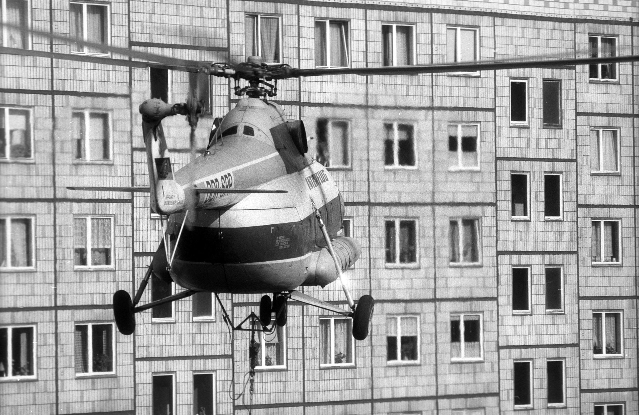 Transporthubschrauber der Interflug fliegt mit Bauteil an einem Wohnhaus in der Karl-Marx-Allee vorbei, Aufnahme von 1988. Foto: Imago/Werner Schulze