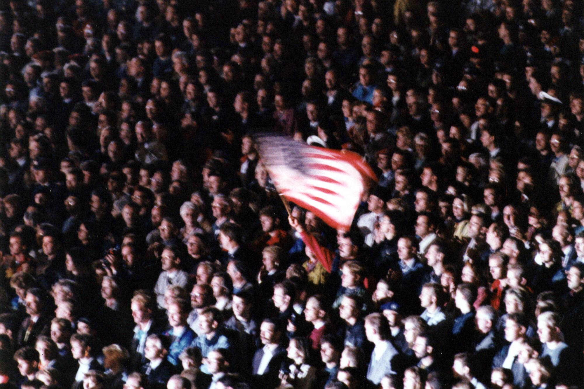 Ein Besucher schwenkt die US-Flagge während des Großen Zapfenstreichs der Bundeswehr anlässlich der Verabschiedung der alliierten Streitkräfte in Berlin, Juni 1994. Foto: Imago/Seeliger