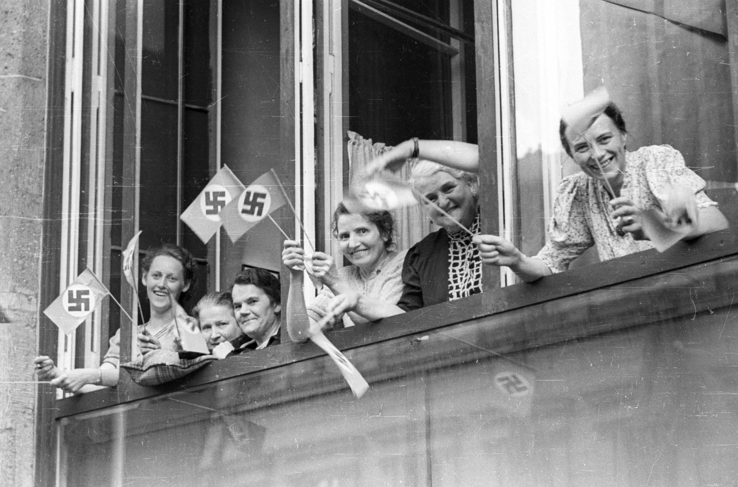 Berlin im Dritten Reich: NSDAP Reichsparteitag – Frauen mit Hakenkreuzfähnchen stehen am Fenster und warten, dass der Führertross vorbeikommt, 1935. Foto: Imago/Horst Müller
